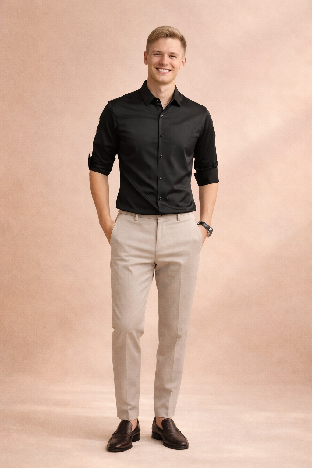Man wearing a black elegant button-down shirt paired with beige trousers in a studio setting