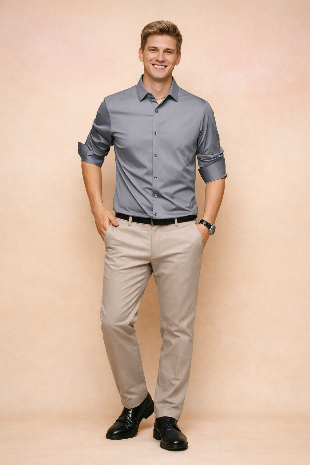 Man wearing a dark gray elegant button-down shirt paired with beige trousers in a studio setting