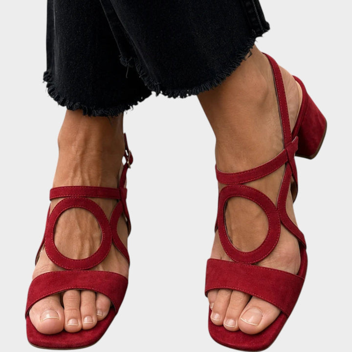 Close up of red block heel sandals with ankle strap and circular cutouts
