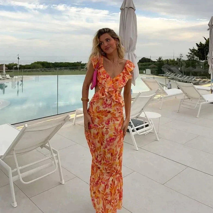 Woman wearing a stylish floral long summer dress by a pool