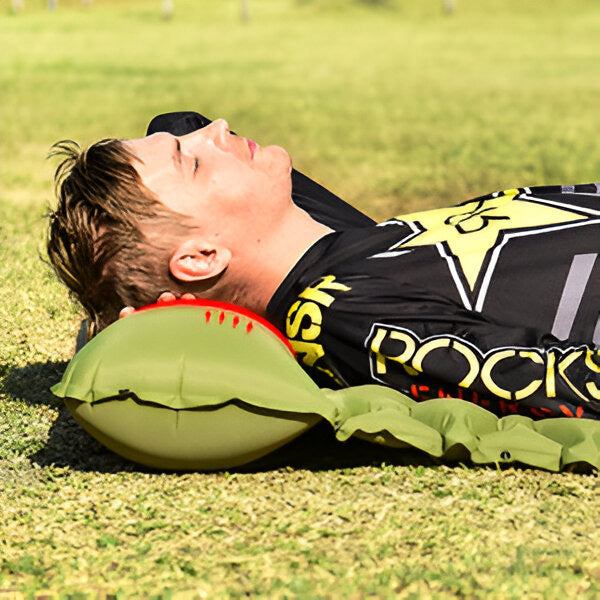 Camper resting comfortably on a green inflatable sleeping pad outdoors