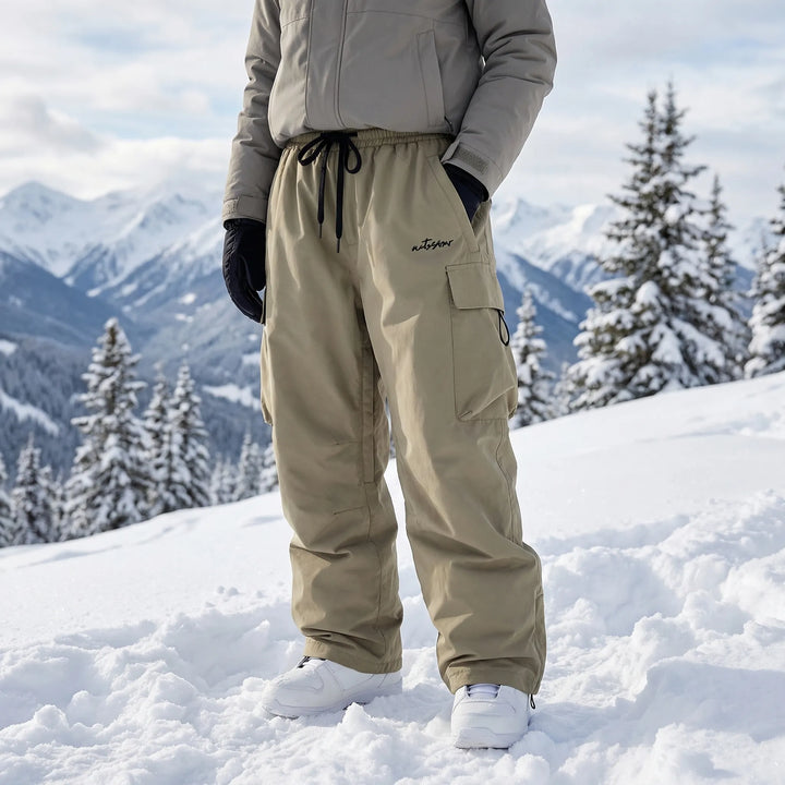 Woman wearing baggy green ski trousers standing in snowy mountain scenery