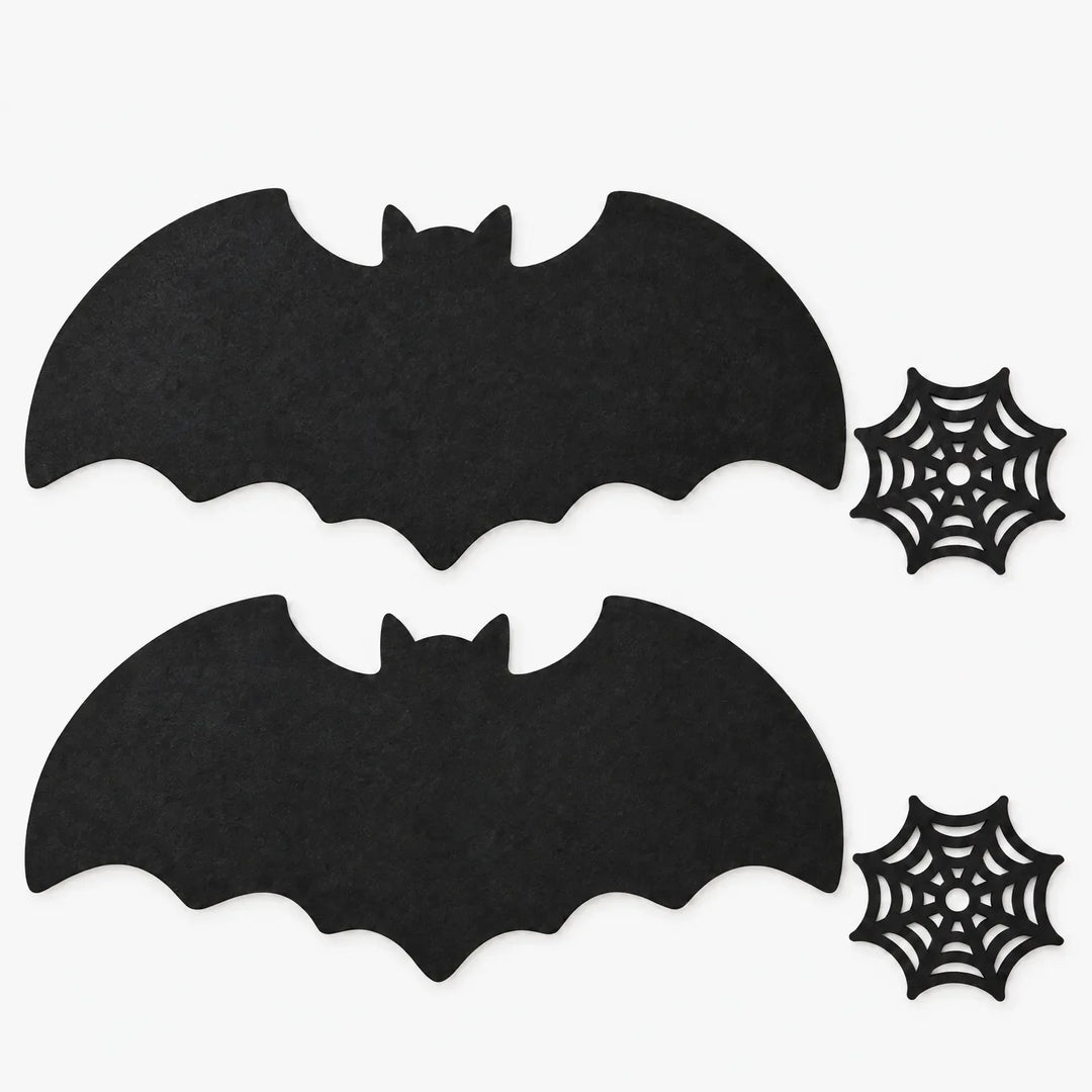 Flat lay of two bat placemats and two spiderweb coasters on a white background