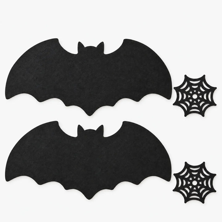 Flat lay of two bat placemats and two spiderweb coasters on a white background