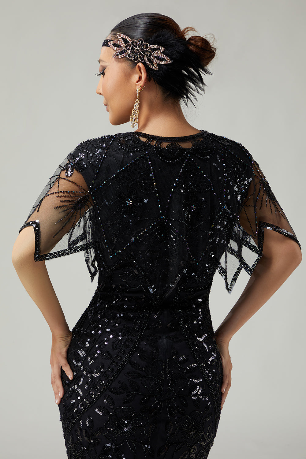 Back view of women's black sequin capelet showing draped mesh design