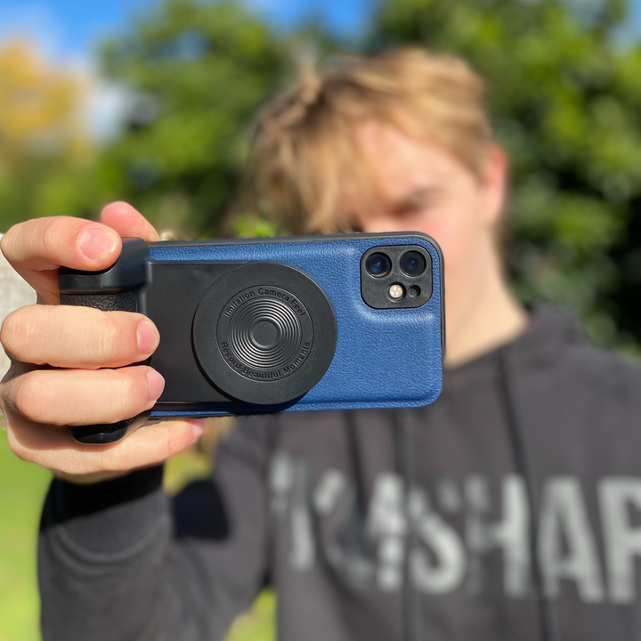 Person holding a smartphone mounted on the selfie grip outdoors