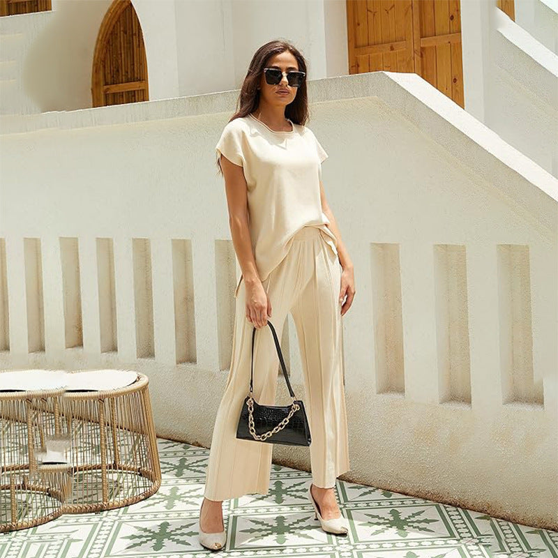 Woman wearing the beige Eleftheria two-piece set with sunglasses and a handbag