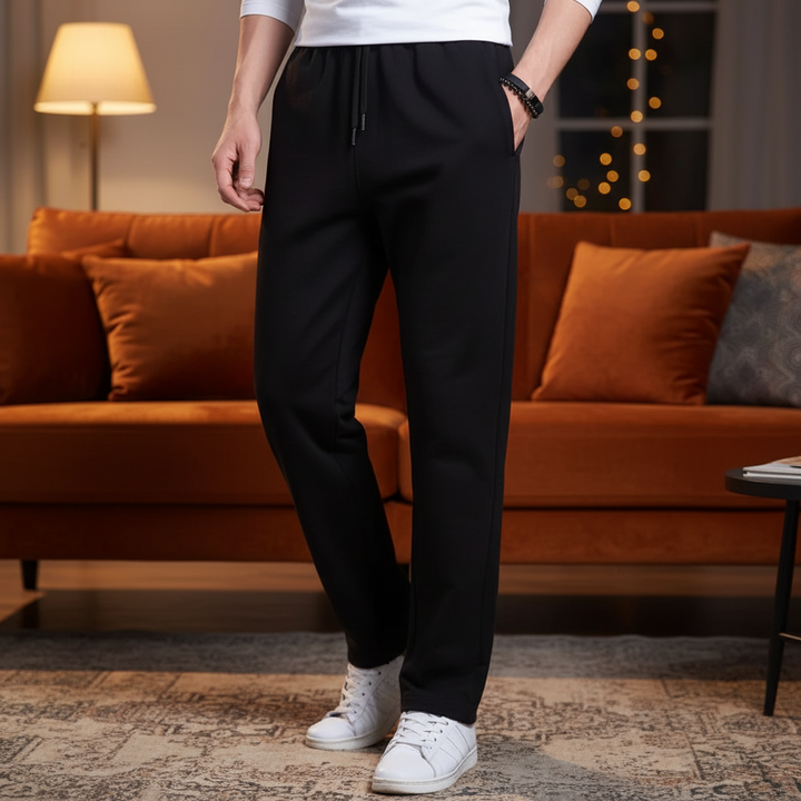 Man wearing black casual joggers and white sneakers standing in a living room
