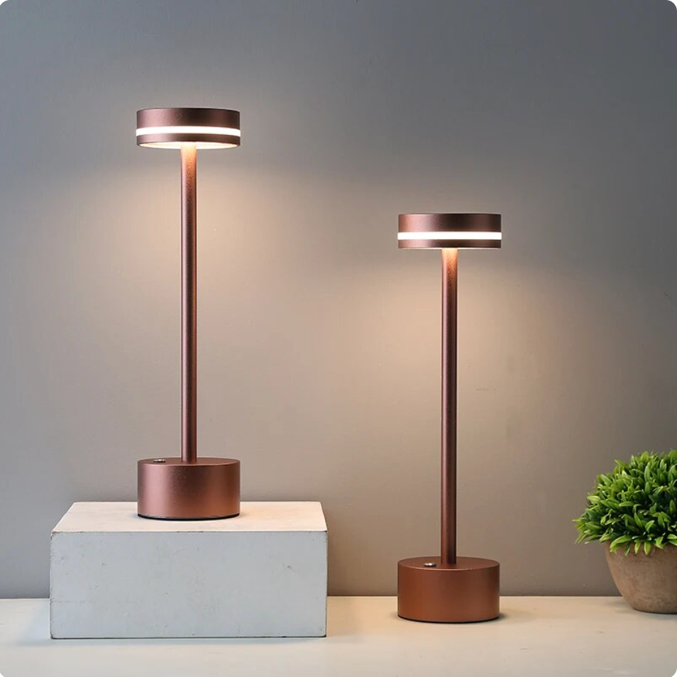 Two bronze Solara cordless touch table lamps showcased at different heights on a display block.