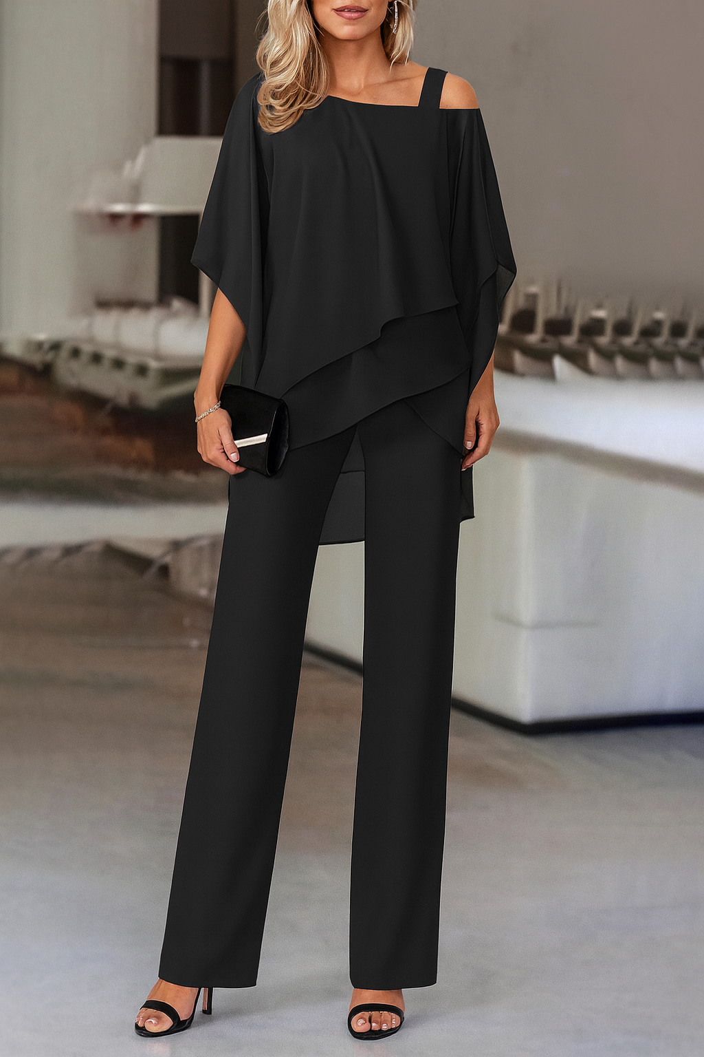 Model wearing a black elegant evening pant set holding a black clutch