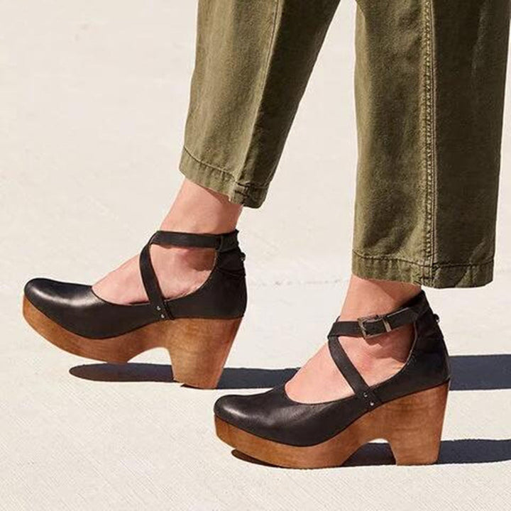 Woman wearing black closed-toe wedge heels with crisscross ankle strap outdoors
