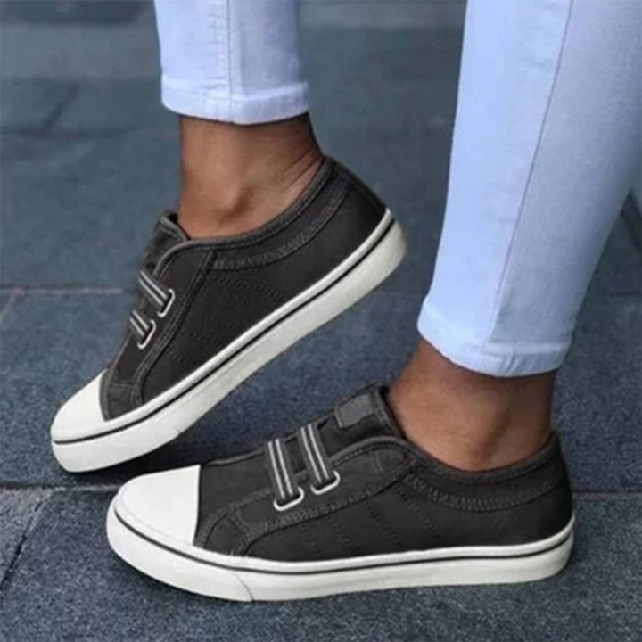 Dark grey women's slip-on sneakers paired with white pants