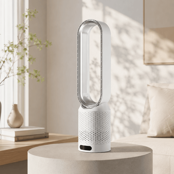 Modern silver bladeless tower fan displayed on a concrete stand in a bright room.