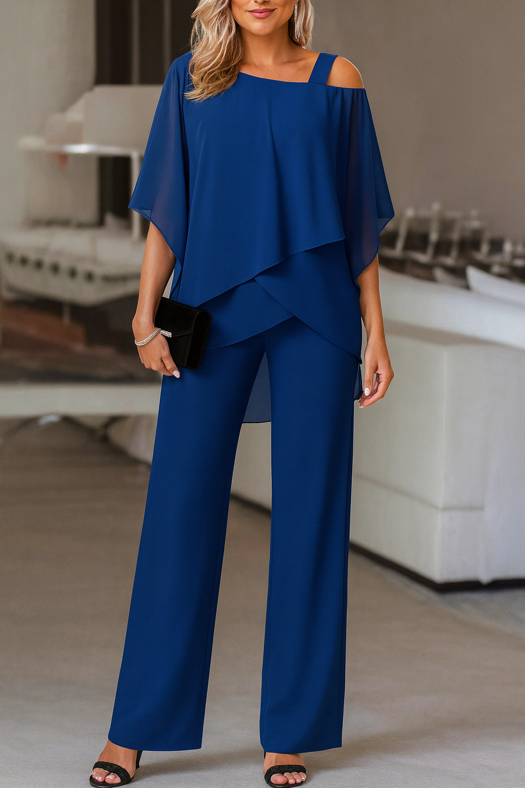 Model wearing a vibrant blue elegant evening pant set with cape overlay