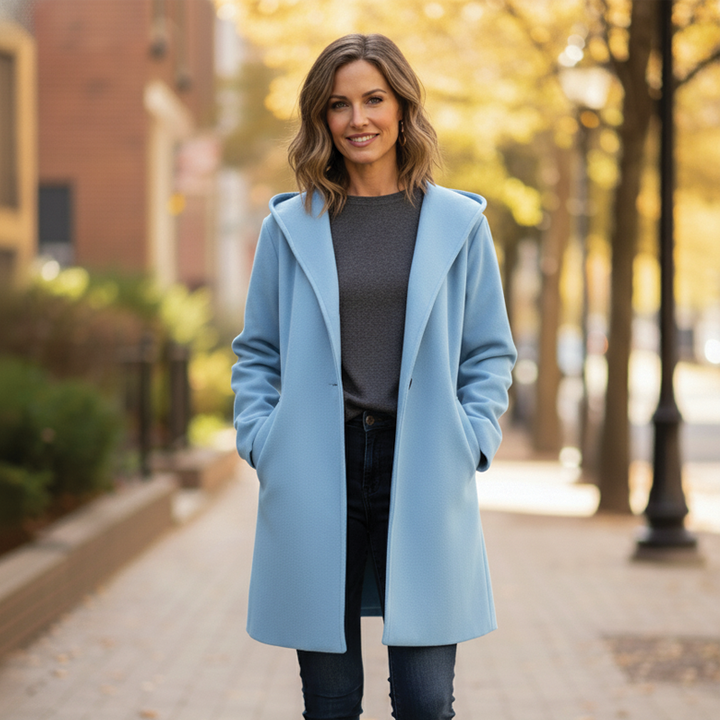 Woman wearing a light blue oversized hooded coat standing outdoors on a sidewalk
