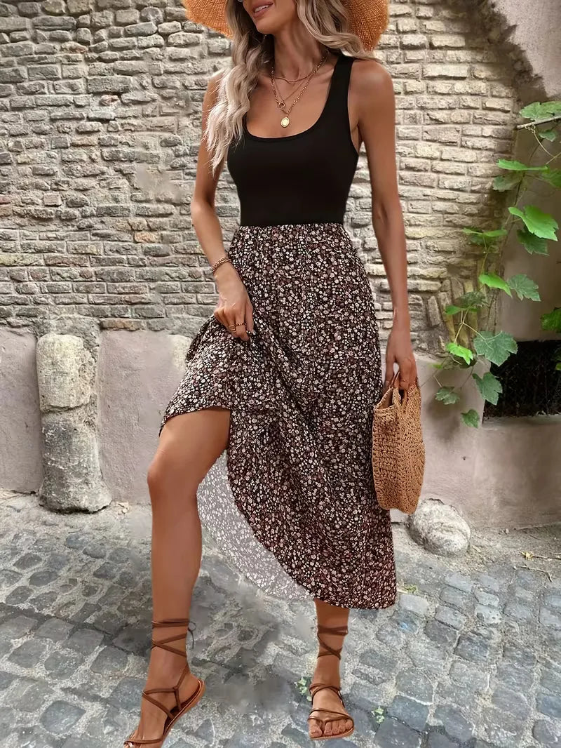 Front view of a woman wearing a bohemian floral maxi dress with a solid black bodice and straw hat