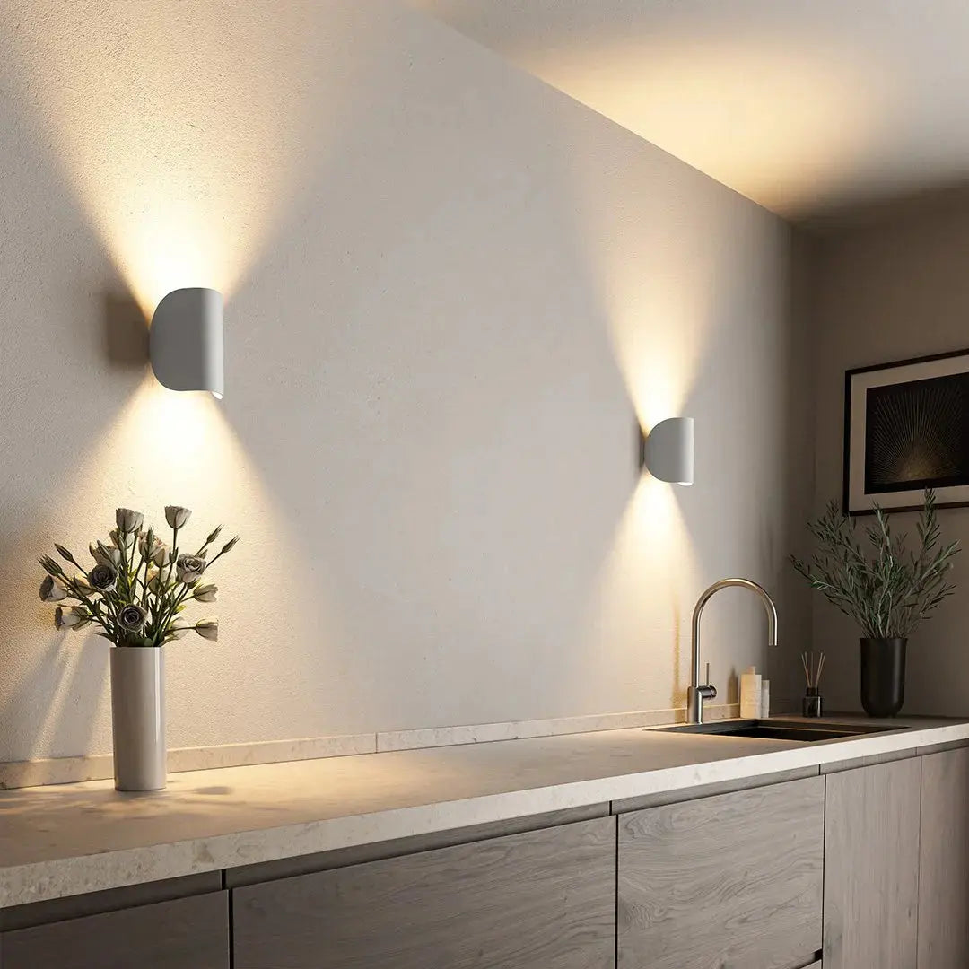 Modern white LED wall lamp mounted on a wall casting warm light in a kitchen setting