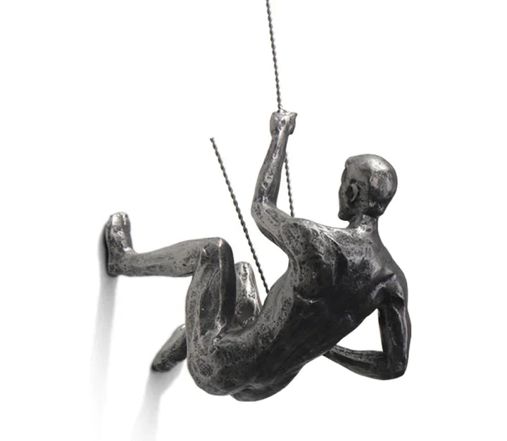 Close-up of a resin climbing figurine mounted on a white wall