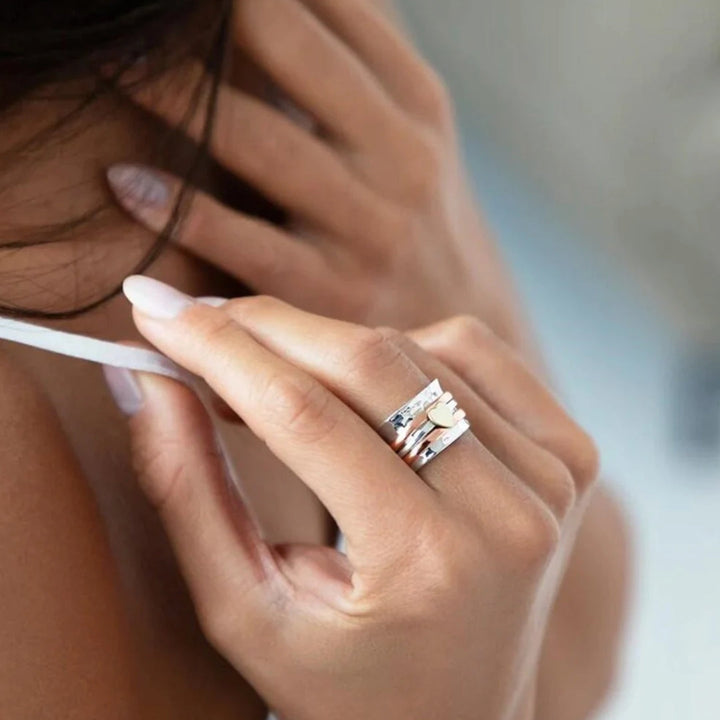 Woman wearing the Amara heart spin ring on her hand against a neutral background