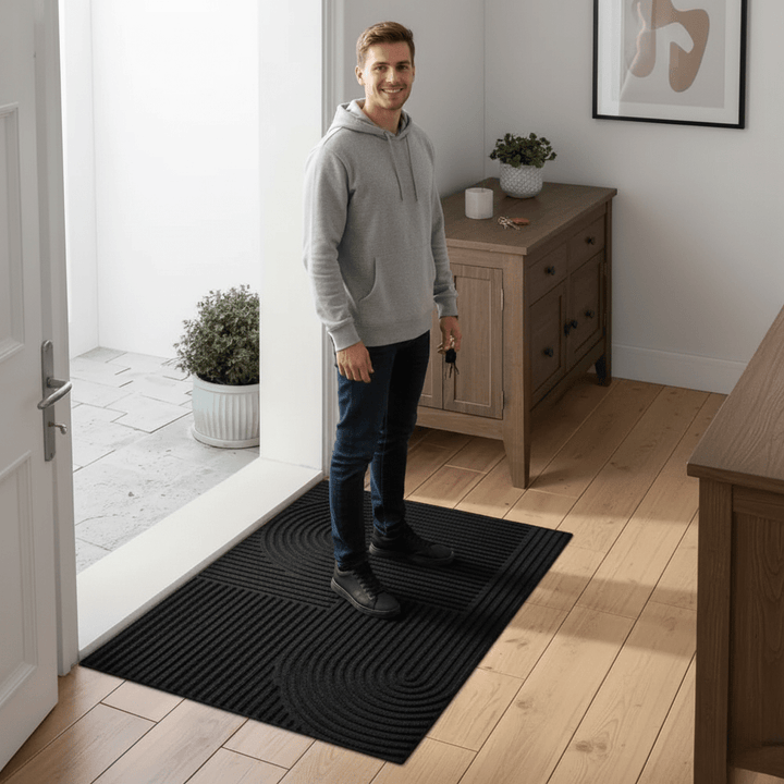 Man standing on the AQUARAY absorbent doormat in a modern hallway