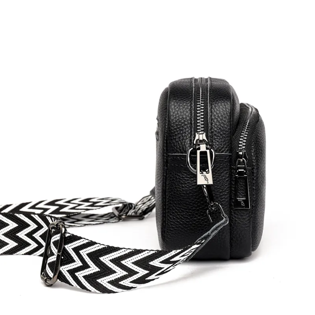 Side profile view of black women's messenger bag with zipper details