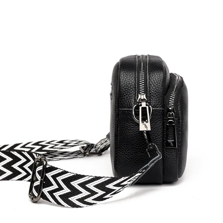 Side profile view of black women's messenger bag with zipper details
