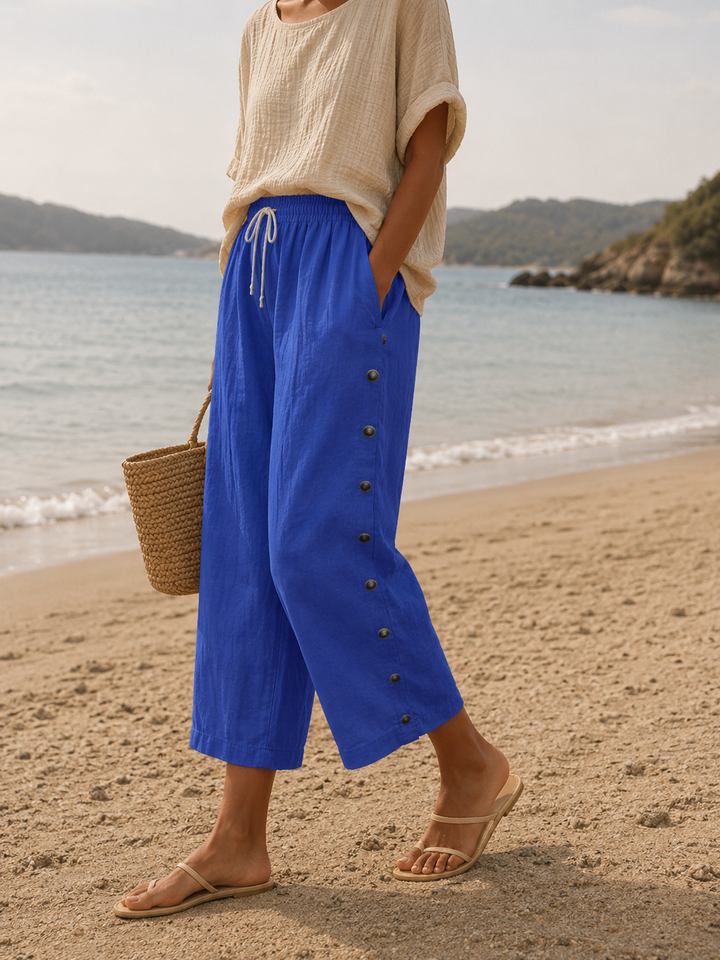 Woman wearing blue casual capri pants with button detail on a beach