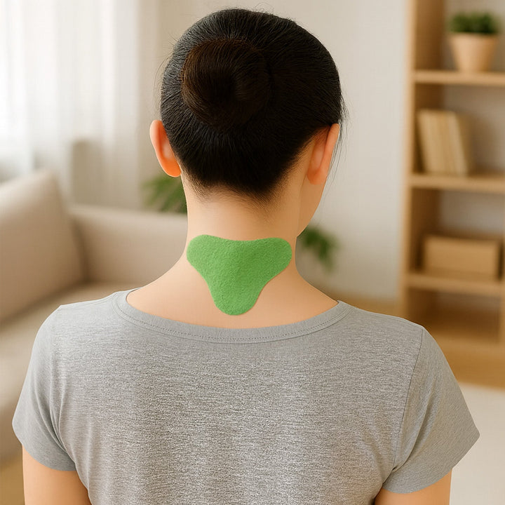 Woman wearing a green herbal cervical spine patch on the back of her neck in a living room.
