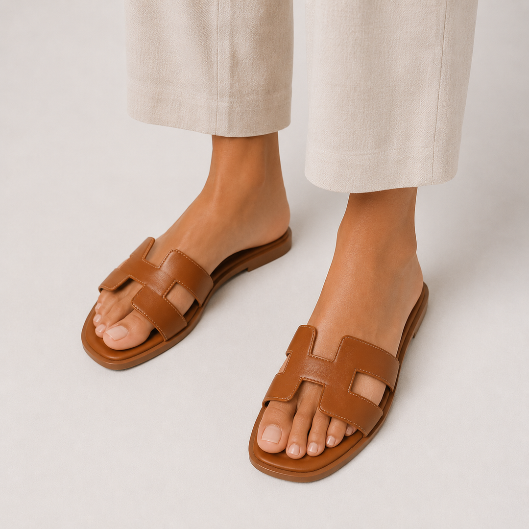 Women wearing brown orthopedic flat slide sandals with H-strap detail