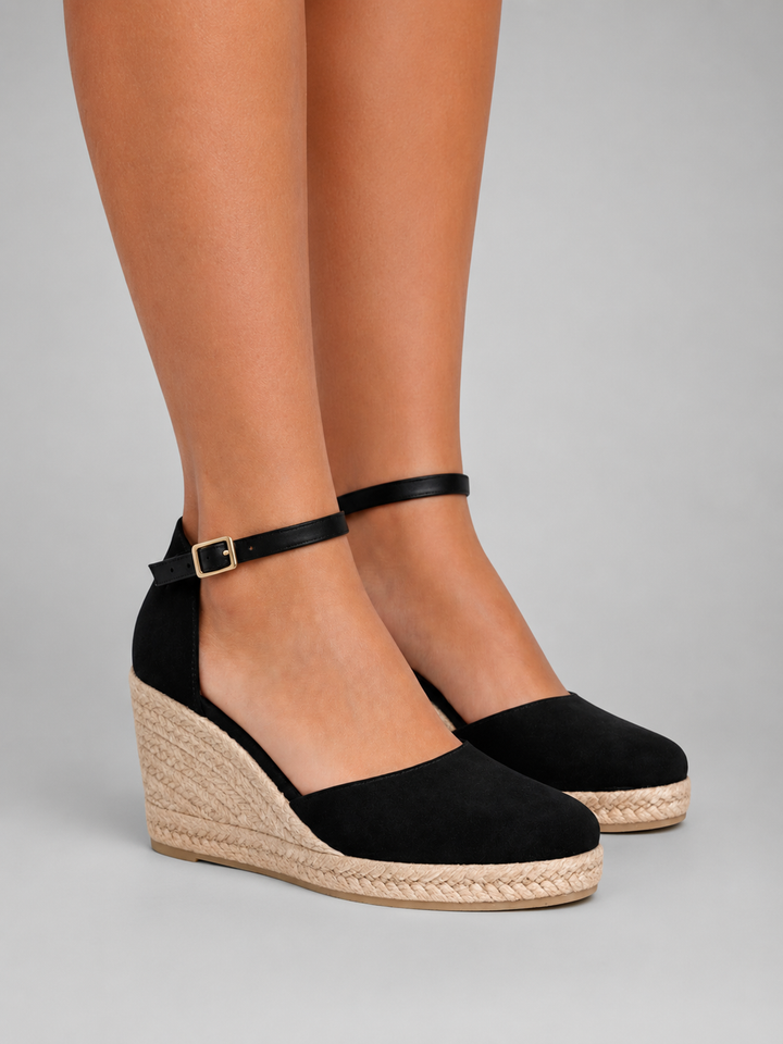 Women wearing black closed-toe wedge espadrille sandals with ankle strap