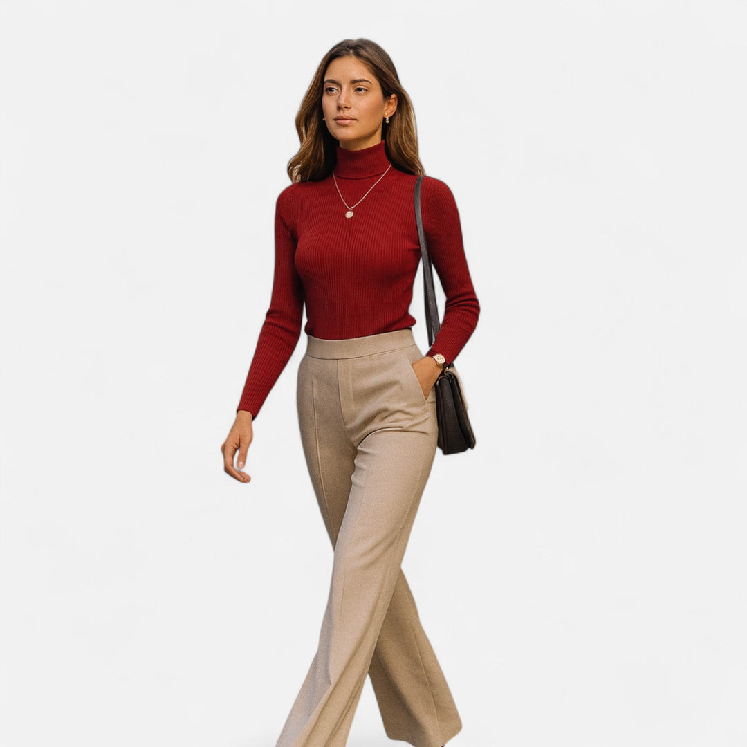 Full-body view of a woman walking in a red ribbed turtleneck sweater and beige pants