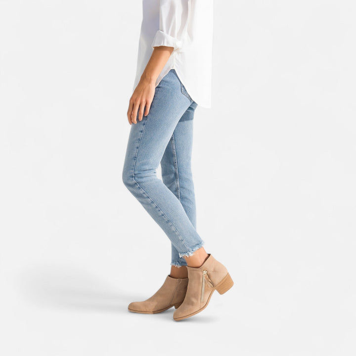 Side profile of a woman wearing beige ankle boots with cropped blue jeans