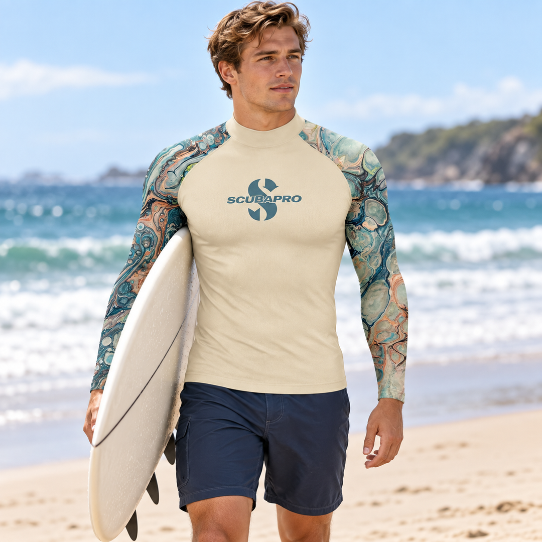 Surfer on beach wearing a long sleeve rash guard with printed sleeves holding a surfboard
