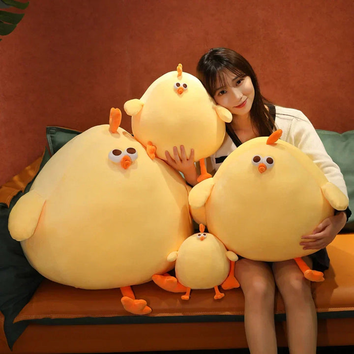 A woman holding multiple sizes of the yellow plush chicken stuffed toy on a sofa