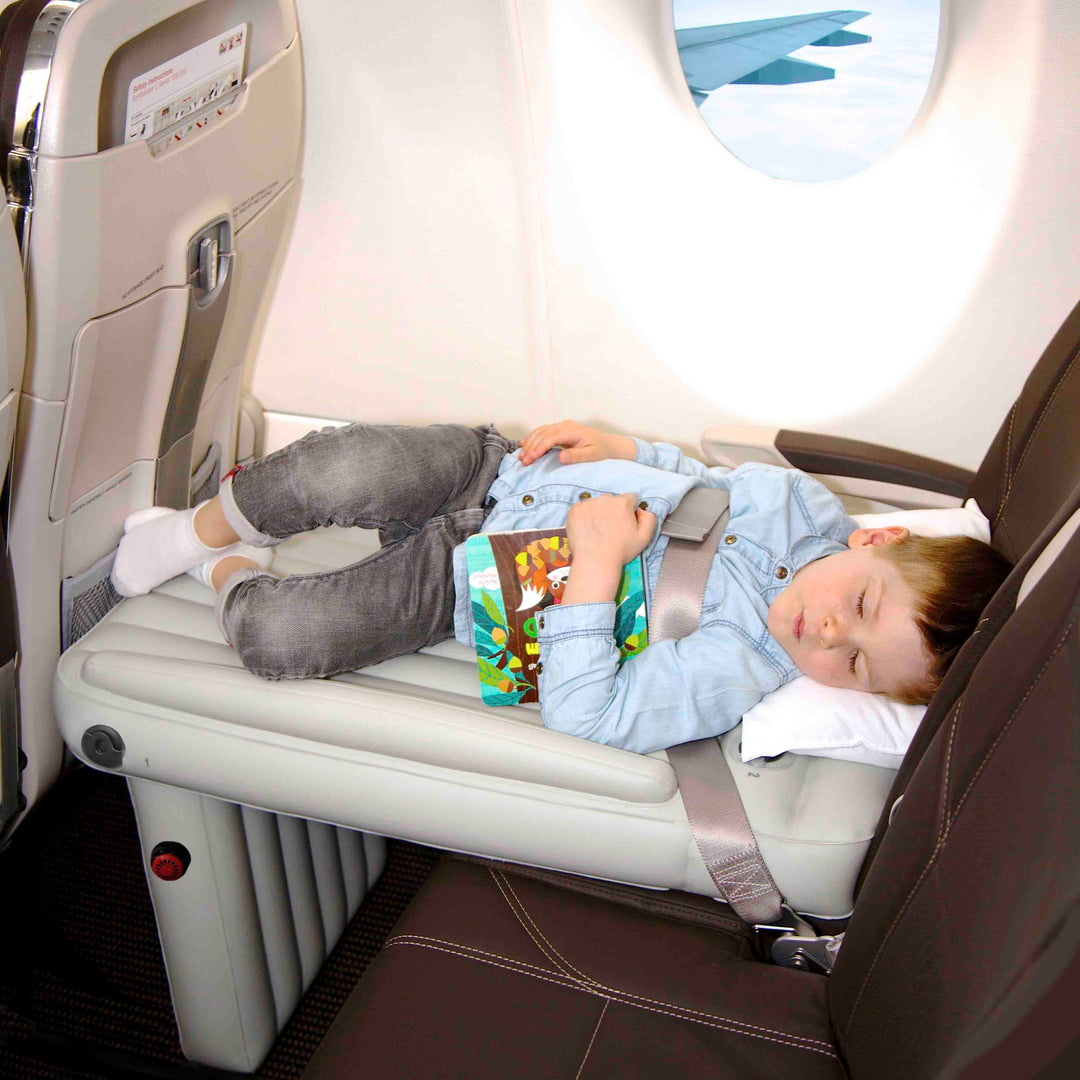 Toddler sleeping soundly on an inflatable airplane travel bed during a flight