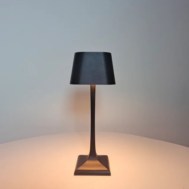 Cordless LED table lamp glowing softly on a modern wooden desk, providing warm ambient lighting