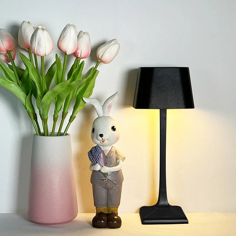 Black cordless LED table lamp next to decorative rabbit figurine and flowers