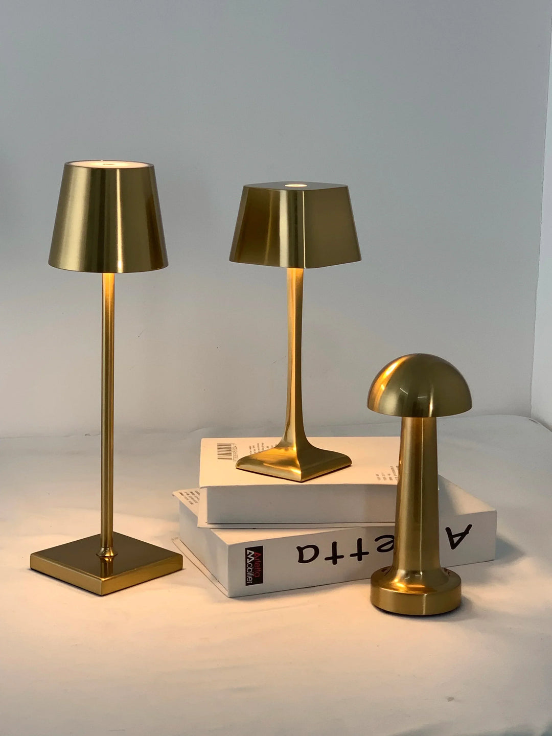 Collection of gold cordless table lamps displayed on white books