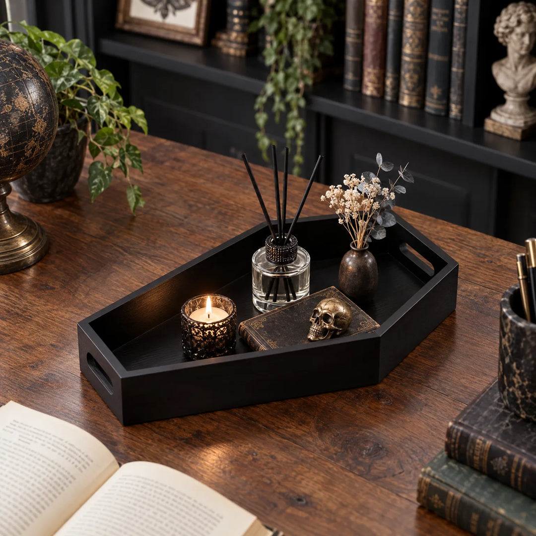 Black wooden coffin serving tray styled with candles and reed diffuser on a dark wooden desk.