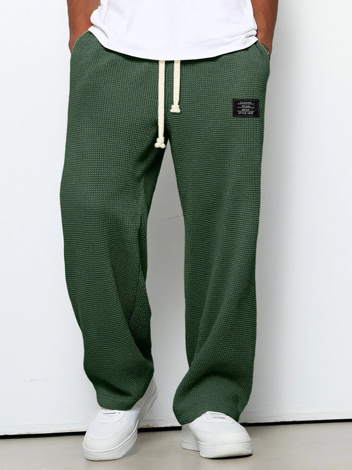 Man wearing dark green textured trousers with adjustable waist