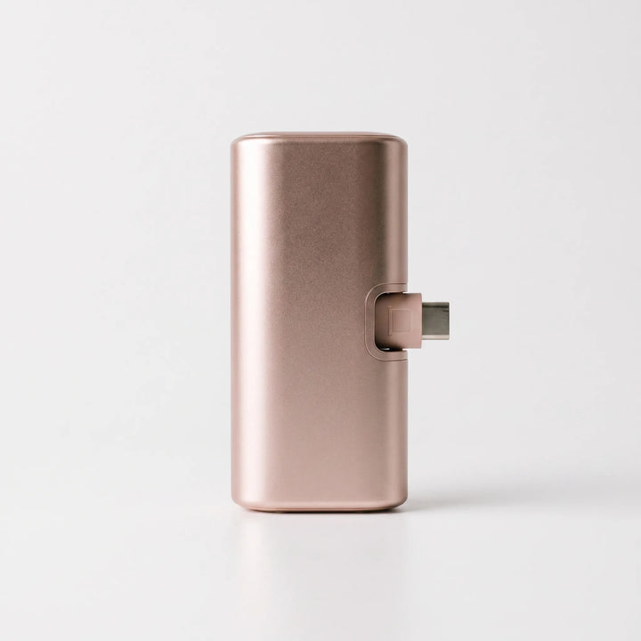 Lightweight capsule charger resting on a surface alongside a charging phone