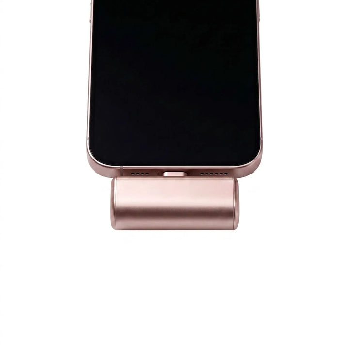 Close-up of a pink portable power bank connected to the bottom of an iPhone