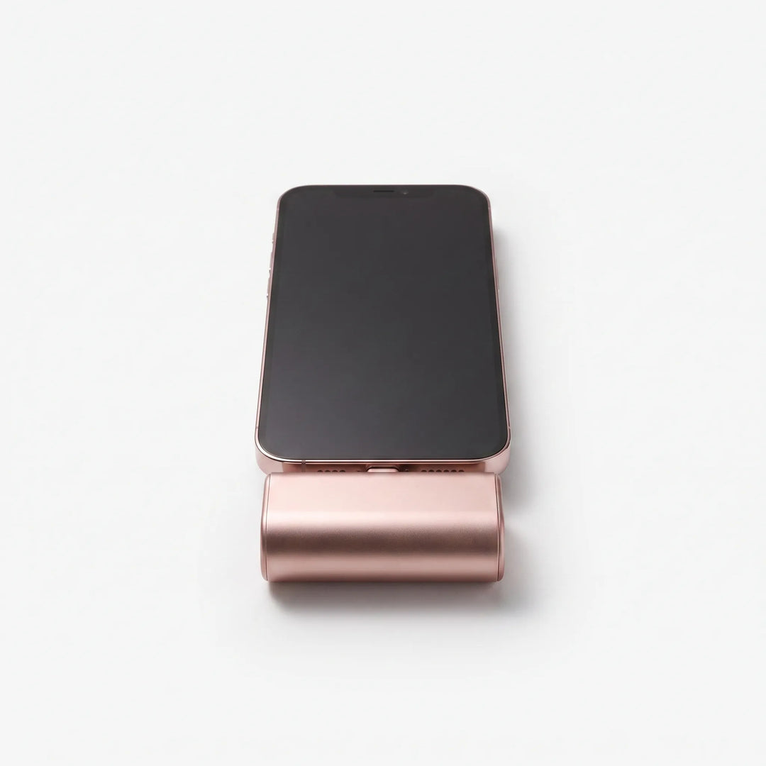Front view of a pink capsule power bank attached to a smartphone on a white background