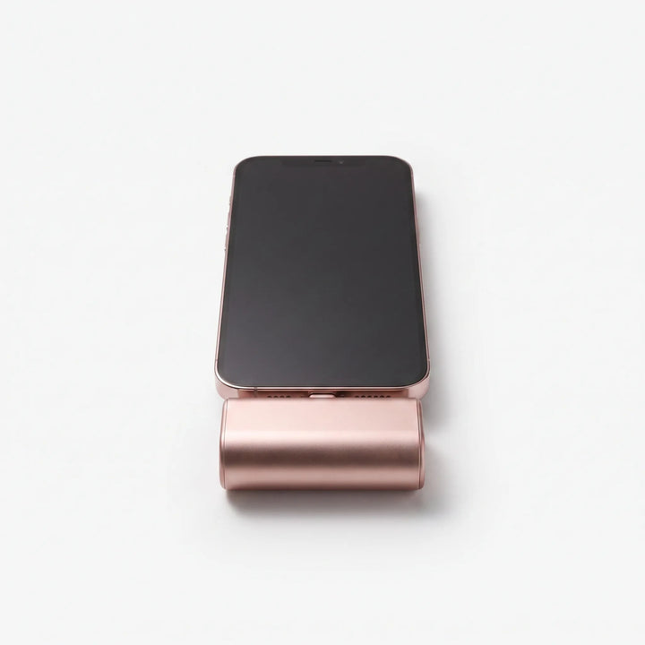 Front view of a pink capsule power bank attached to a smartphone on a white background