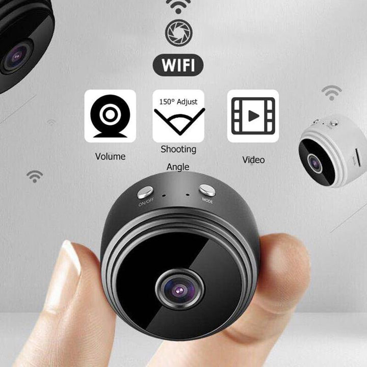 Fingers holding the ultra-compact security camera highlighting its wide-angle lens and control buttons.