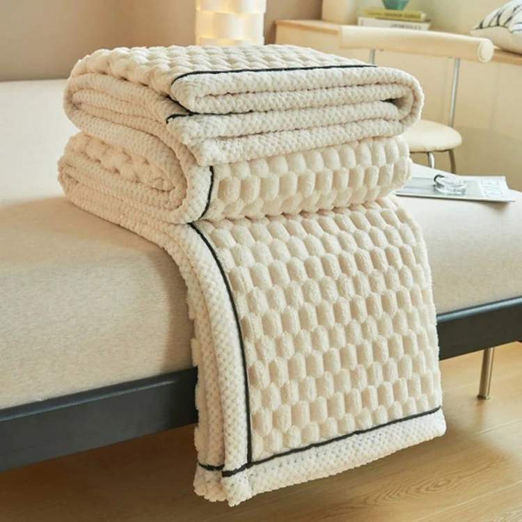Folded ivory CloudTouch weighted blanket on a bed