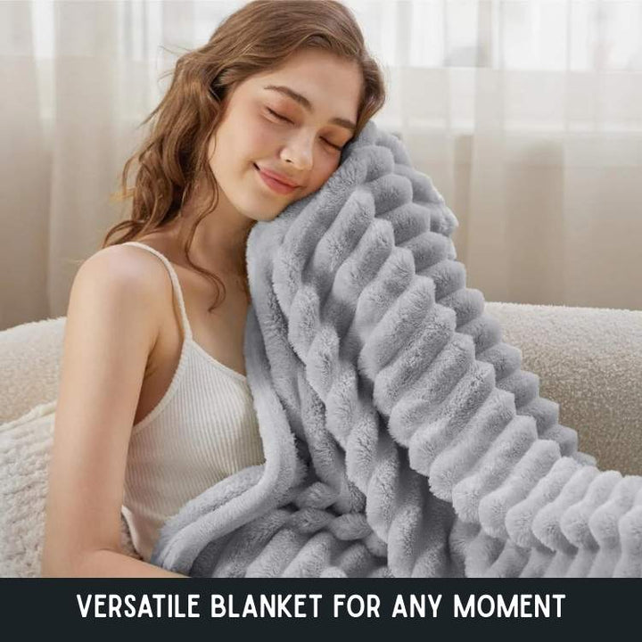 Woman holding a light grey plush striped blanket near a sofa