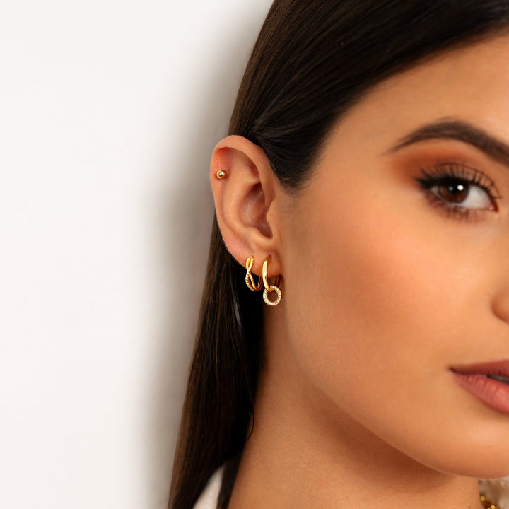 Close-up profile of a woman wearing gold linked hoop earrings in her ear lobe