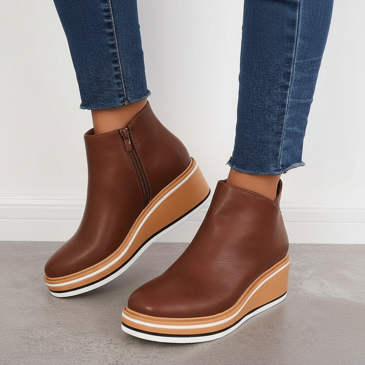 Close up of brown platform ankle boots with side zipper against white background
