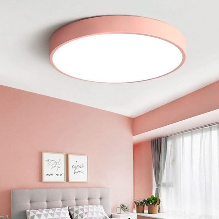 Pink round flush mount LED ceiling light in a cozy modern bedroom setting